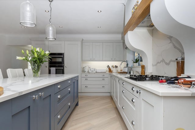 The spacious kitchen has Shaker style units, with a central island and dining unit, and marble worktops.