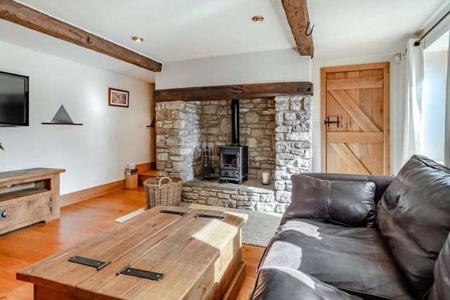 A family room with cosy wood burner within a stone fireplace.