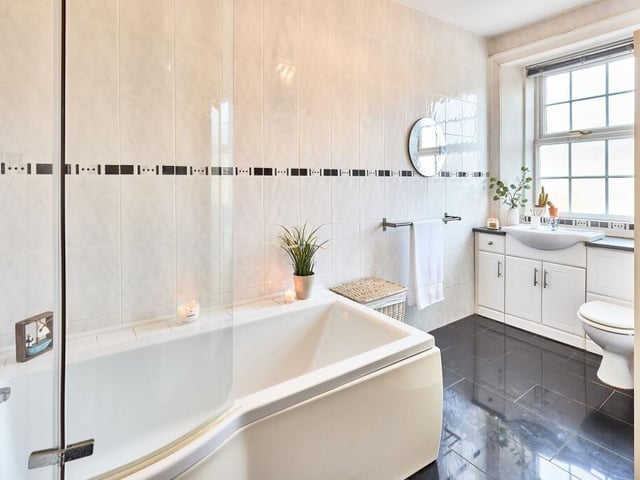 The family bathroom completes the first floor of the main property and has a three-piece white suite comprising of a wide bathtub with curved screen and shower overhead, plus a built-in vanity unit housing the basin and w.c.