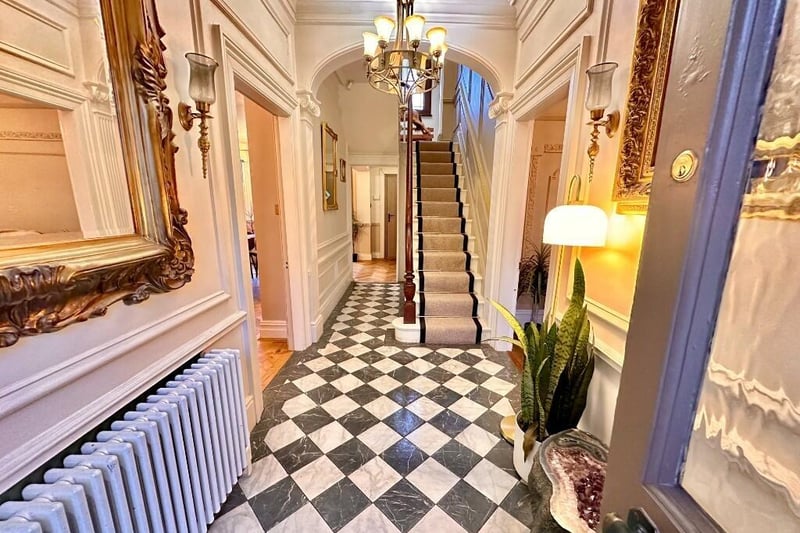 A bright and welcoming hallway with a decorative archway at the foot of the staircase.