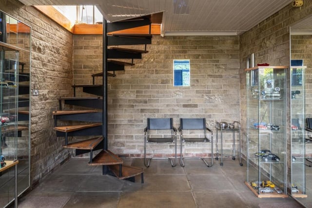 A winding staircase rises to the first floor from the hallway with stone-clad walls.