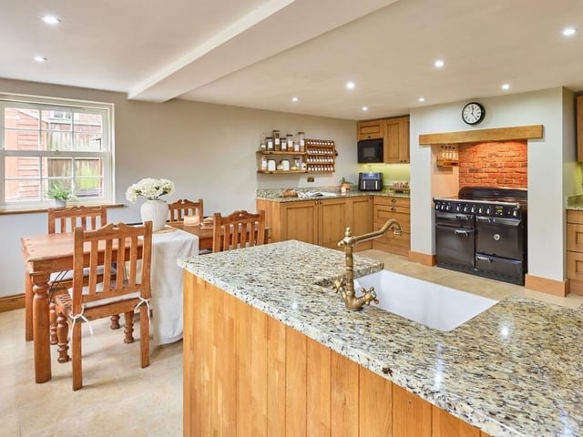 The spacious kitchen features natural solid oak cabinets and statement vintage elements including a Belfast sink and AGA range cooker nestled in the hearth.