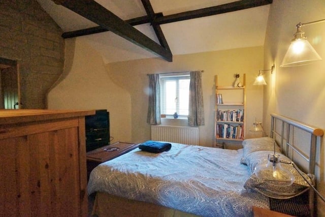 A double bedroom with beams and open stone wall feature.