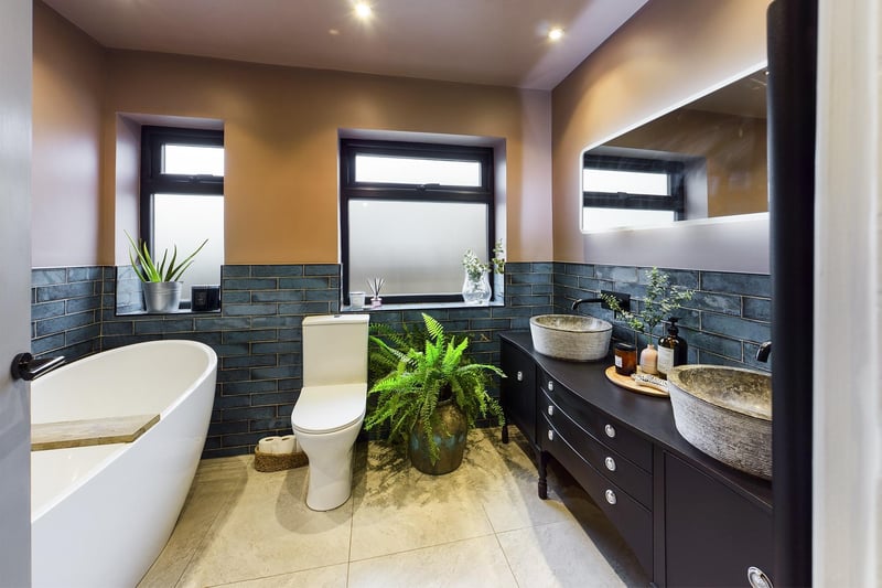 A contemporary bathroom with free standing bath and twin wash basins with vanity unit.