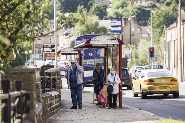 Passengers wait at a bus stop on Huddersfield Road, Brighouse.