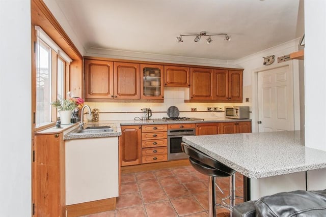 This fully fitted kitchen includes a range of wall and base mounted units with complimentary work surfaces over incorporating breakfast bar, plumbing for dishwasher, space for under counter appliance, a stainless steel sink and drainer with a mixer tap, an integrated oven and grill, a gas hob and a cooker hood over.