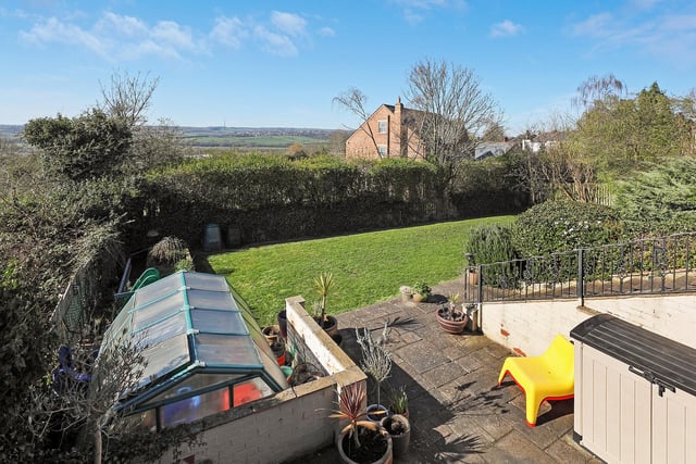 An enclosed garden with a view stretching beyond to Emley Moor.