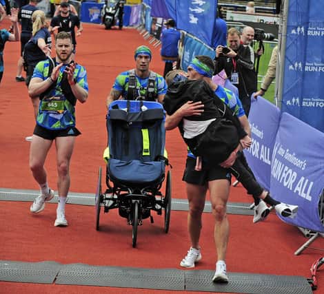 Rob Burrow gets a kiss from his friend Kevin Sinfield as he carries him across the finish line