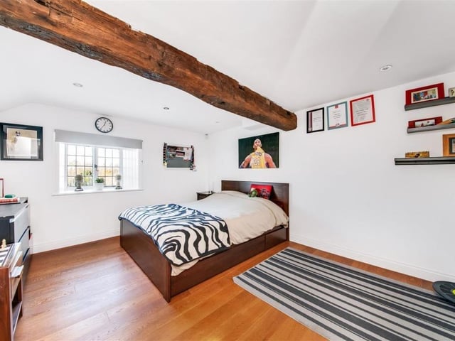 A beamed bedroom with shelving and plenty of floor space.