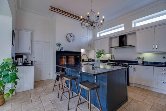 The stylish breakfast kitchen with central island has a warming stove within a feature fireplace.