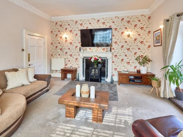 The dual-aspect lounge has tall ceilings, a marble fireplace and a bespoke panelled window seat. A set of French doors lead out to the garden, flooding the room with light all day.