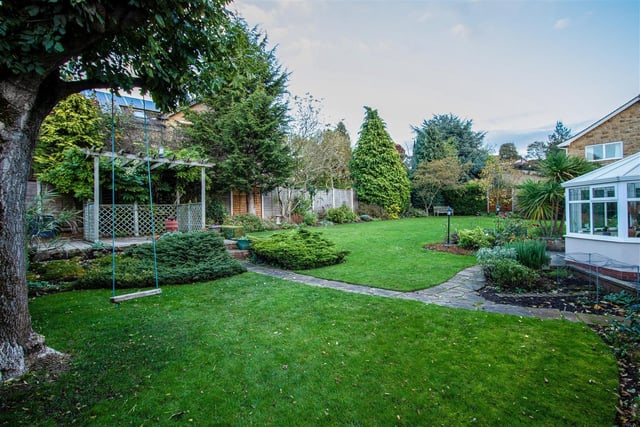 The established gardens include seating areas - one with a pergola.