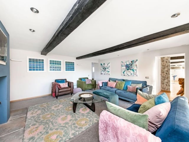 The beamed living room has a cosy woodburner, and doors out to the gardens.
