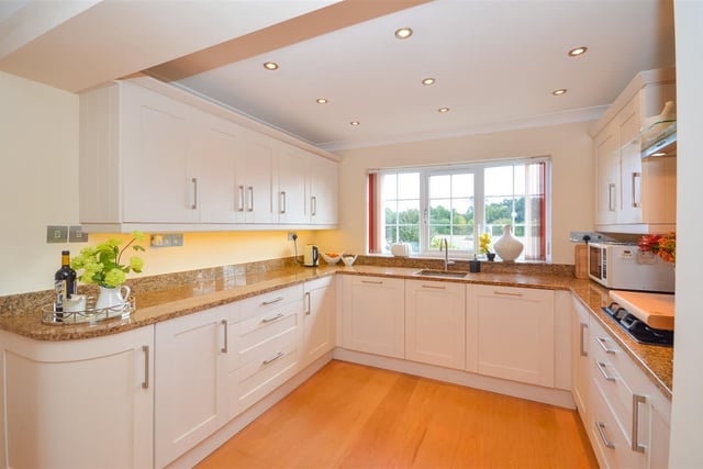 A modern kitchen has fitted units with granite work surfaces and integrated appliances.