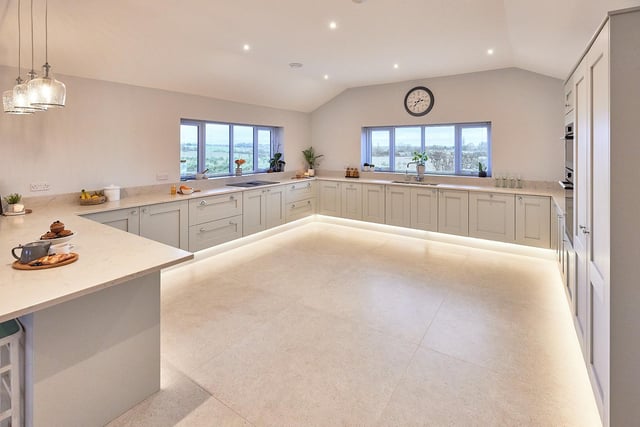A modern, double aspect shaker-style kitchen has dove-grey units and integrated appliances.