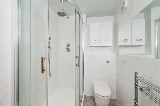 The en suite features a three piece suite comprising of a shower cubicle with rainfall shower, a low level flush WC, and a wash basin with a chrome waterfall mixer tap.