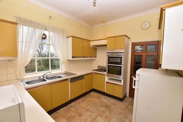A kitchen with fitted, mustard colour cabinets.