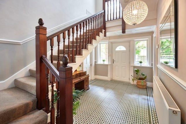 The property's bright hallway has Victorian style floor tiles, with a wooden spindle staircase leading to the first floor.