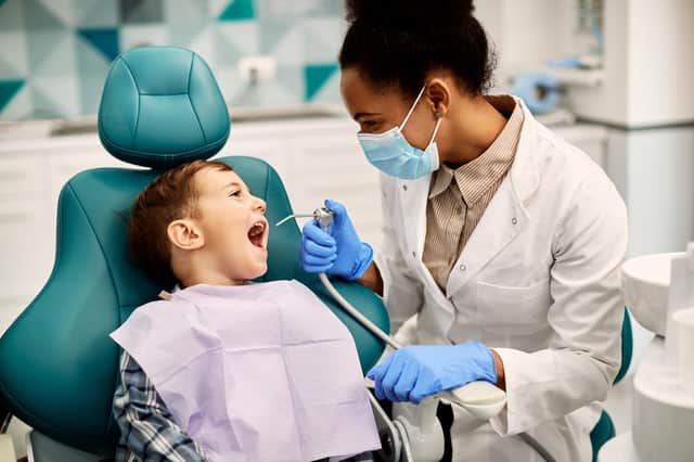 Happy little boy having his teeth checked by female dentist during appointment at dental clinic. 