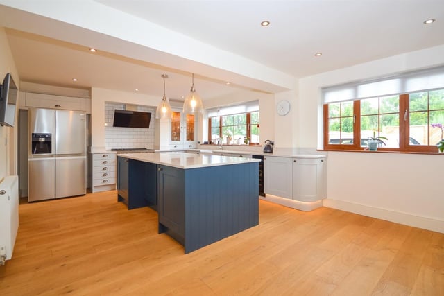 A large central island is a feature of the kitchen, with fitted units and stone worktops.