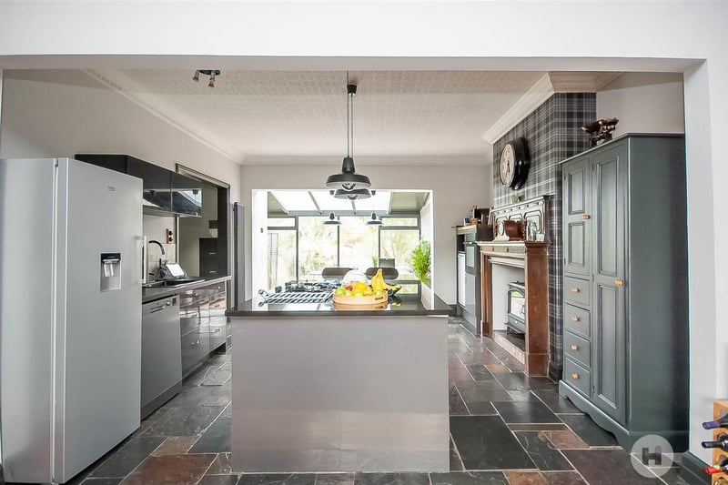 The bright and modern kitchen has a living flame effect gas stove within an original period fireplace.