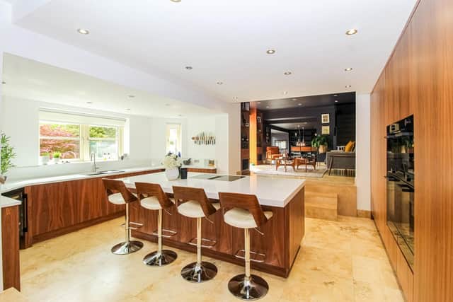 A modern, open plan kitchen has bespoke, walnut-fronted units and leads to a living room, family room then dining area.