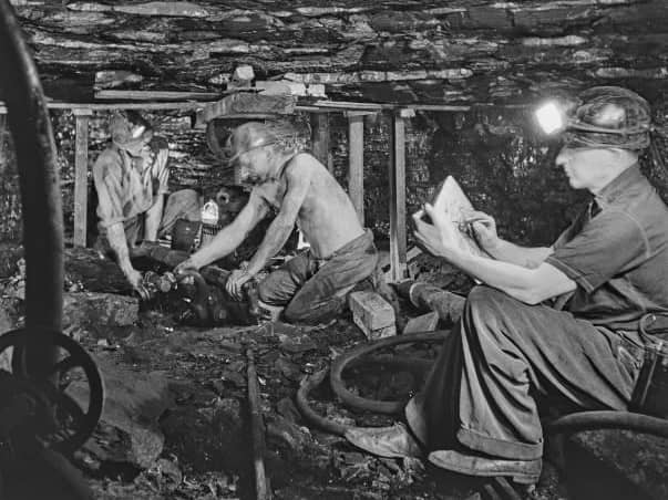 English artist Henry Moore (1898-1986) makes sketches of miner Jack Hancock and a colleague at work on the bottom level of Wheldale Colliery, a coal mine in Castleford near Wakefield in Yorkshire, England during World War II on January 7, 1942. Henry Moore has been commissioned by the War Artists' Advisory Committee to make drawings and paintings of coal mining subjects. (Photo by Reuben Saidman/Popperfoto via Getty Images)