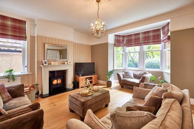 The bay-fronted lounge has a central log burner, with wooden flooring, and period decorative features.