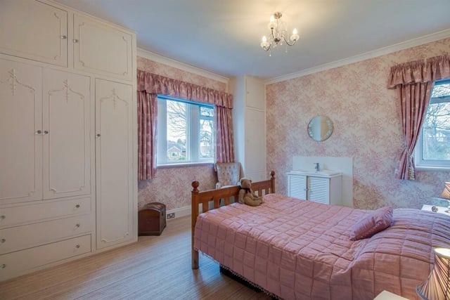 The principal bedroom includes windows to two sides, a central heating radiator and two double fronted built in wardrobes with a matching dressing table.
