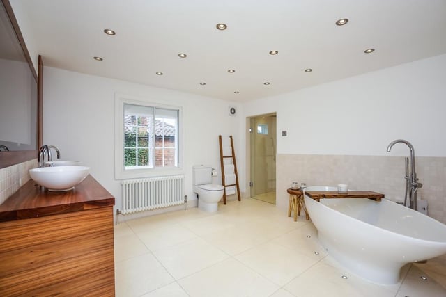 A concealed television, twin hand wash basins, a walk-in rainfall shower and a double ended bath feature in this bathroom with underfloor heating.