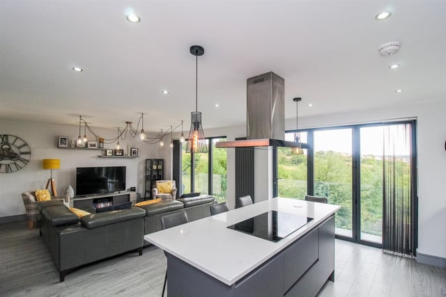 A balcony with glass balustrade fronts the open plan kitchen with living area, and looks out over countryside.