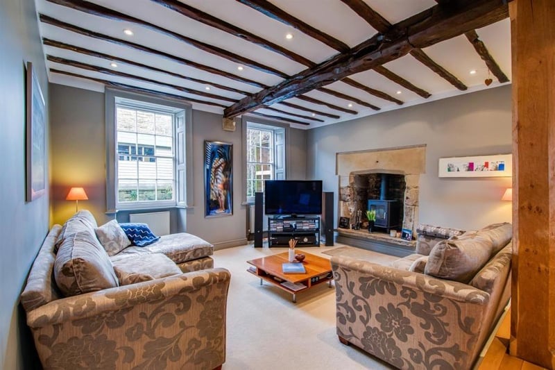 The sitting room features a raised fireplace with a stone interior and hearth - housing a large cast iron wood burning stove, a beamed ceiling and a step up to the adjoining dining area.