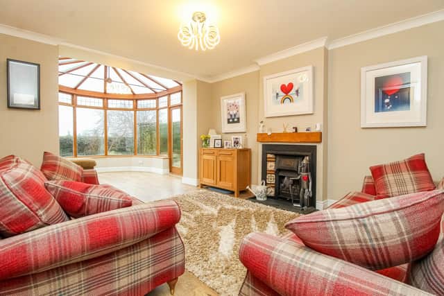 The sitting room, with tiled fireplace and living flame gas fire, leads to the conservatory.