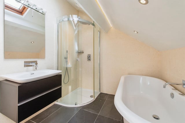 A bathroom with curved corner shower unit and free-standing bath tub.