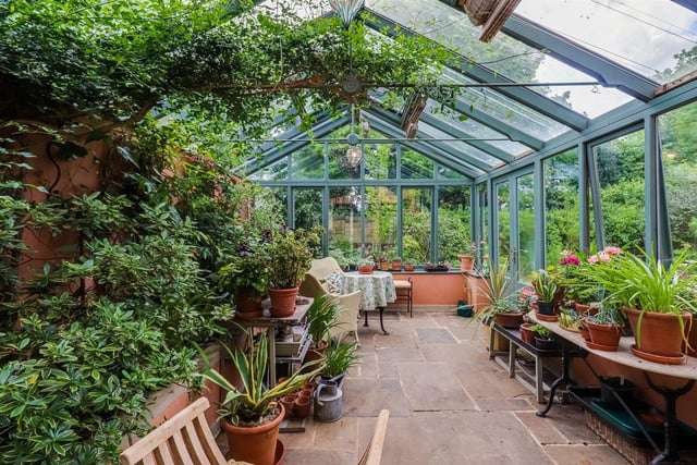 The conservatory is surrounded by the greenery of the garden.