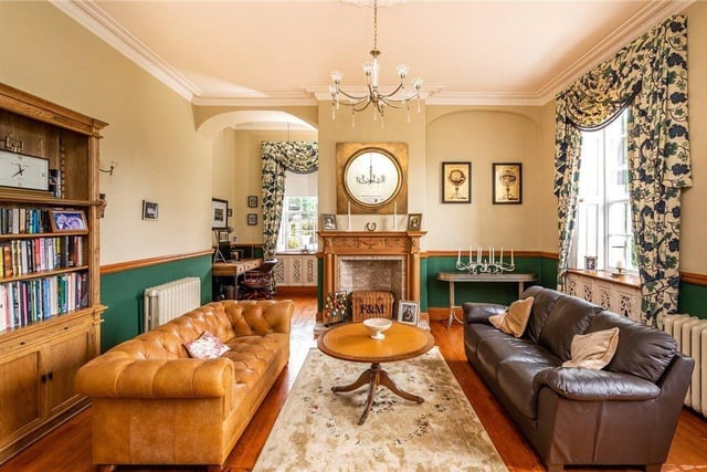 The sitting room has an Adam style fireplace and original timber flooring, with large windows overlooking the grounds.