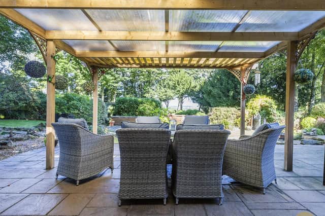 A covered outdoor seating area with attractive garden surroundings.