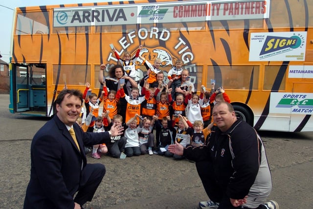 Phil Stone, managing director of Arriva Yorkshire and Dave Woods, coach of Castleford Tigers, unveil the bus in the club's colours with players Frank Watene, Andrew Henderson and Steve Crouch with children from Wheldon Road Infant School.