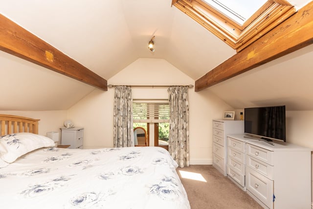 A spacious double bedroom with ceiling beams and a skylight window.