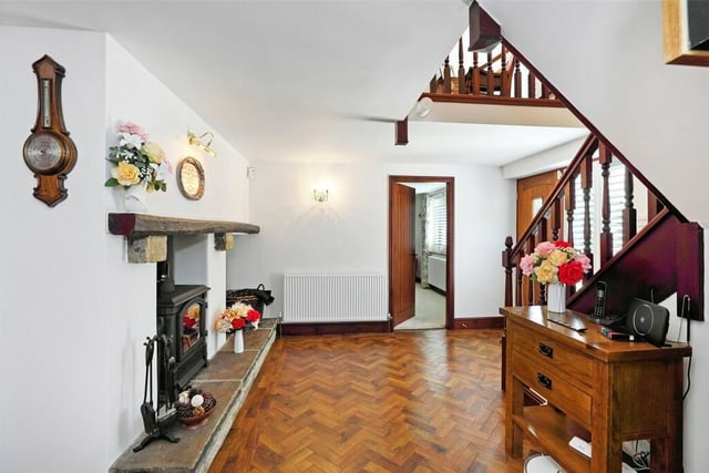 The spacious hallway features double glazed window, Karndean flooring, a feature fire place with a log burner and an open staircase with understairs storage cupboard.