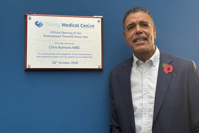 Chris Kamara MBE with the plaque inside Trinity Medical Centre.