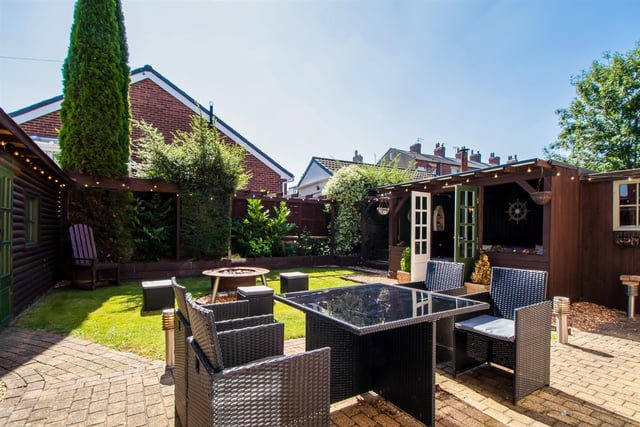 A lawned garden with patios also has a summer house and home bar at the rear of the house.