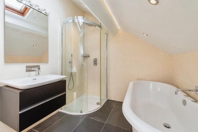 The proeprty's bathroom features a four piece fitted suite comprising of a curved corner shower cubicle with rainfall shower. a freestanding roll top bath with mixer tap, a low flush WC, and a wash hand basin with a vanity unit.