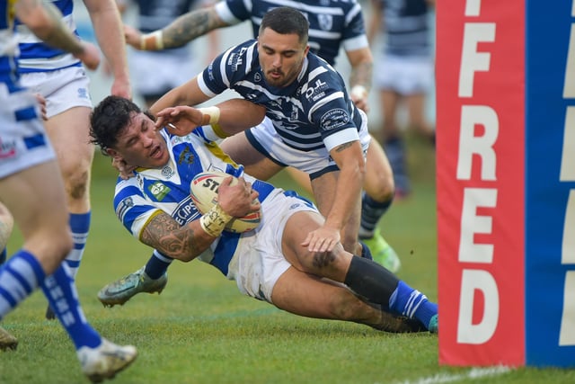 Adam Tangata, of Halifax Panthers, picks up the ball and is tackled by Caleb Aekins.