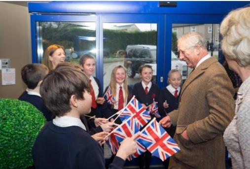 Children with flags welcome the Prince of Wales.