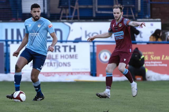 Nathan Curtis gets on the ball for Ossett United while Pontefract Collieries' Jack Greenhough points where he thinks the ball is going.