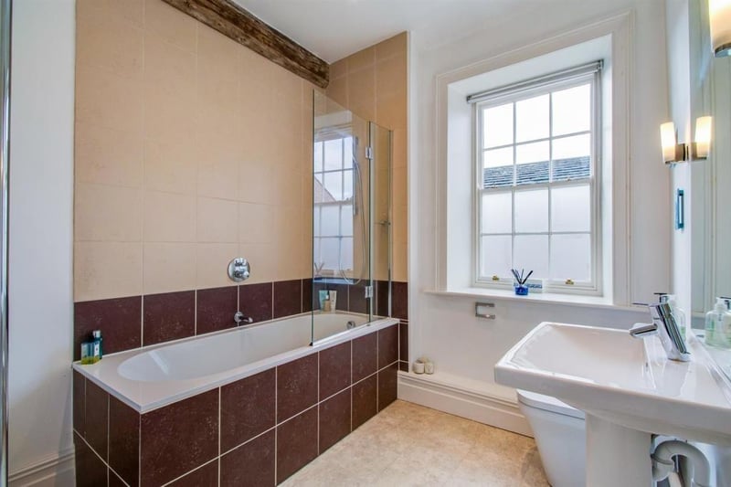the family bathroom features a white and chrome three piece suite which compromises of a panelled bath with a shower over and hinged glazed screen, a pedestal wash basin and a low suite w.c.