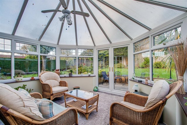 The conservatory has doors out to a patio seating area, and the wider garden.