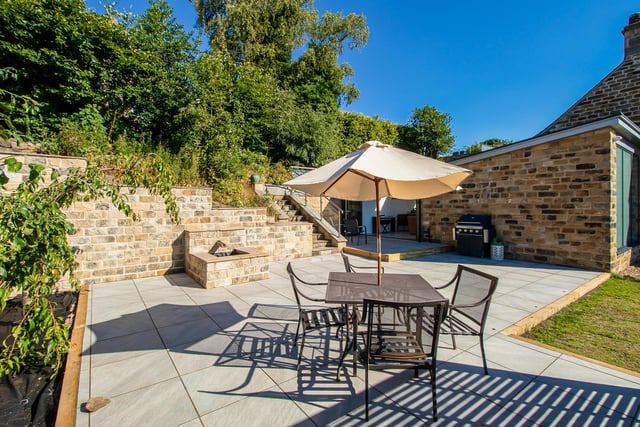 A rear garden area with porcelain tiled floor and uplights, has oak railway sleeper edges, with a water feature. Steps lead to a raised, Yorkshire stone paved seating area with stunning views over Newmillerdam, and a paved roof terrace overlooking the property.