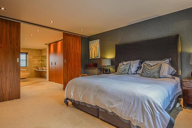 The spacious bedroom area has sliding doors to a walk in wardrobe which further flows into a vast ensuite bathroom .